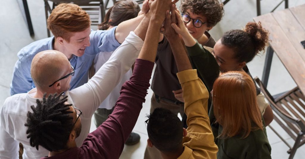 A diverse group of professionals high-fiving in a modern office, showcasing teamwork and collaboration.